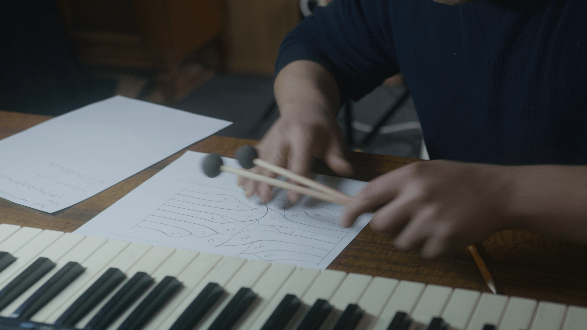Musician testing notes on a keyboard during the drum-tuning process