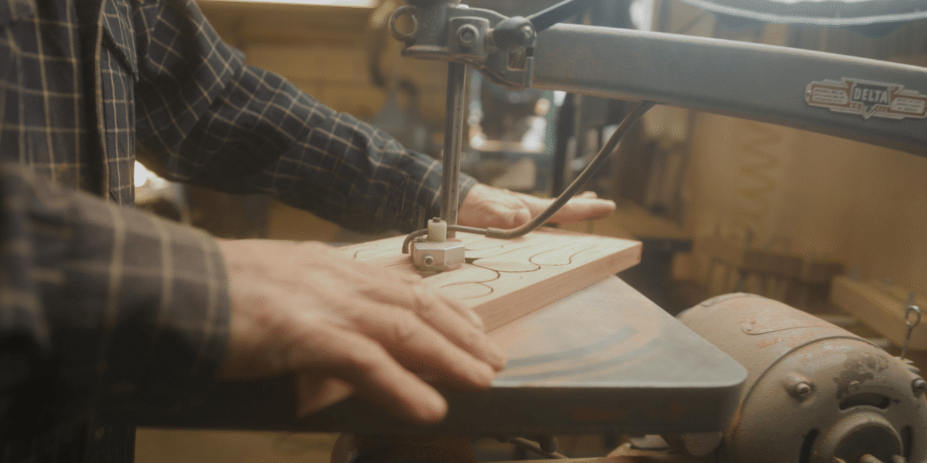 Craftsman shaping a wooden drum face by hand in the workshop