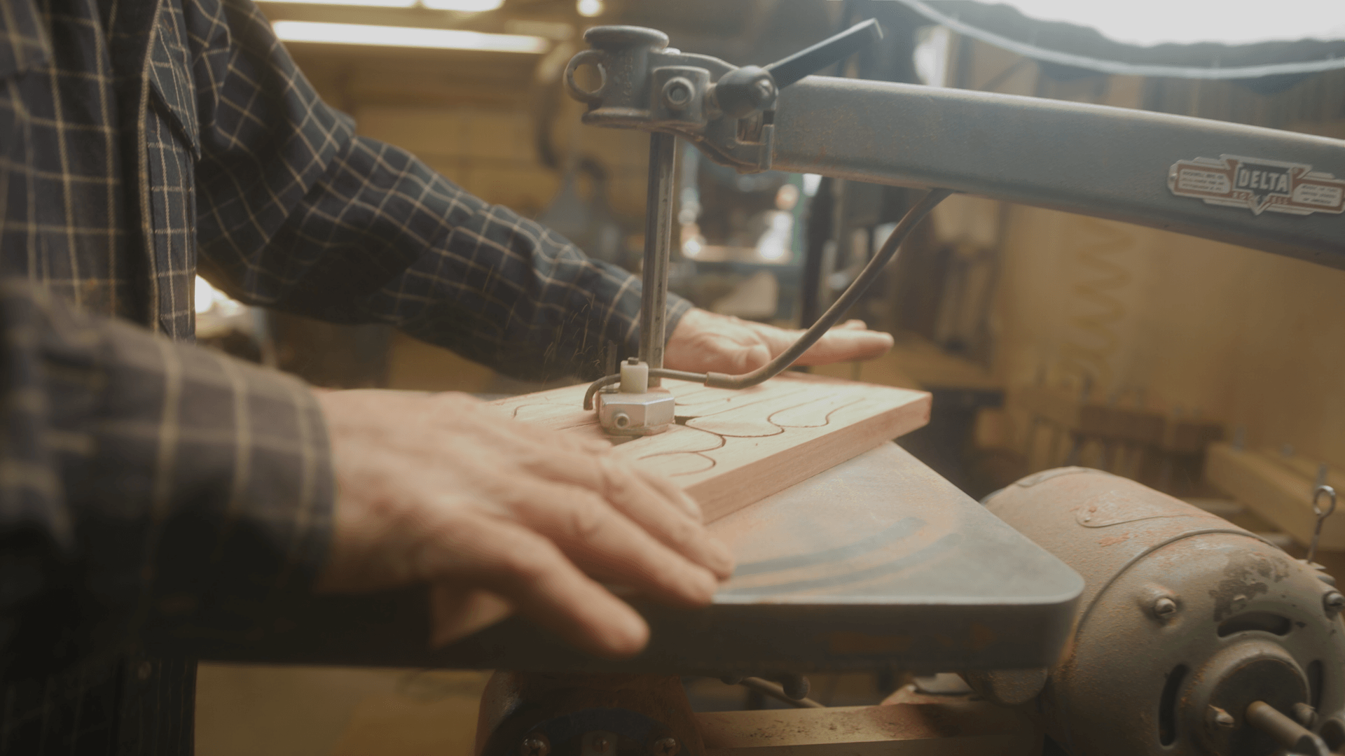 Craftsman shaping a wooden drum face by hand in the workshop