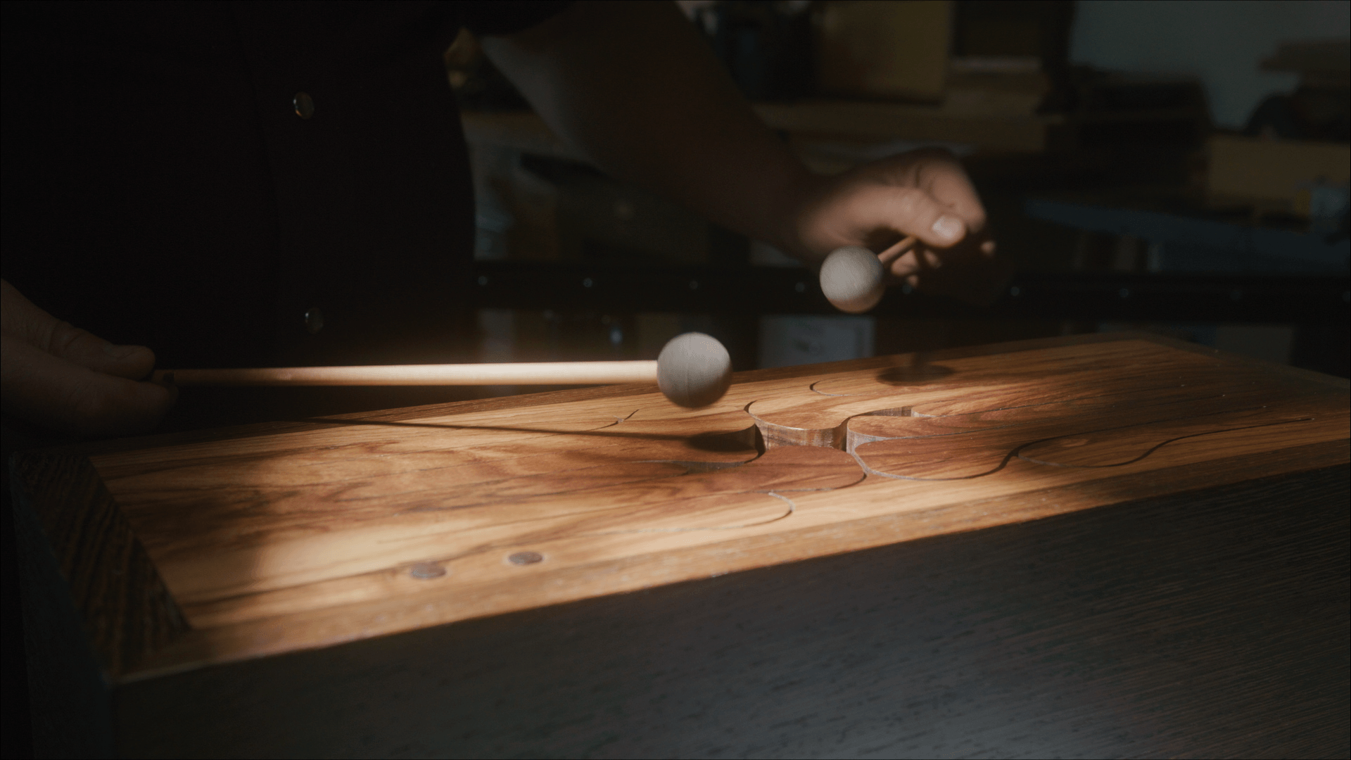 Close-up of a mallet striking a handcrafted wooden percussion instrument